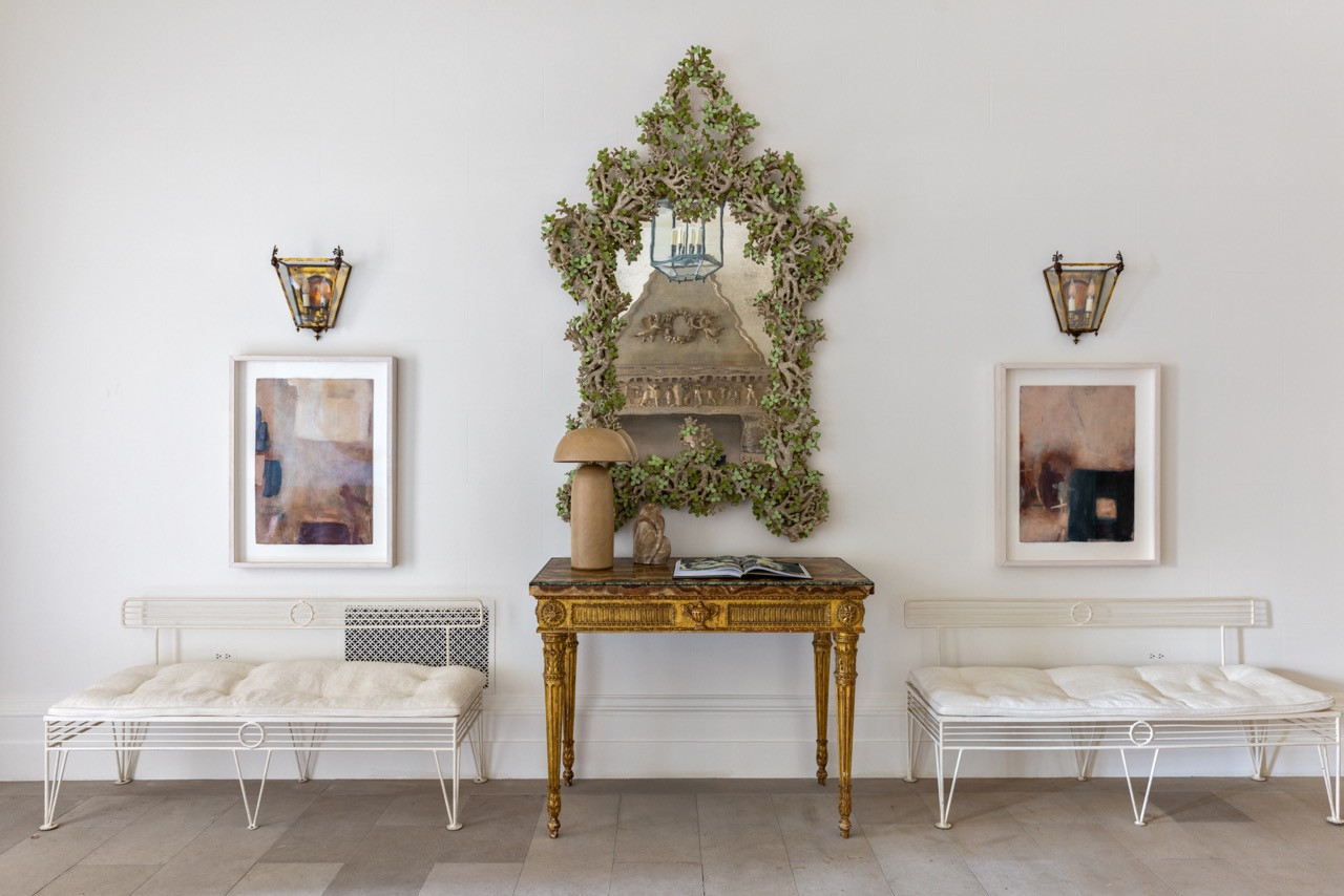 The same console vignette, flanked by a pair of iron benches and abstract paintings