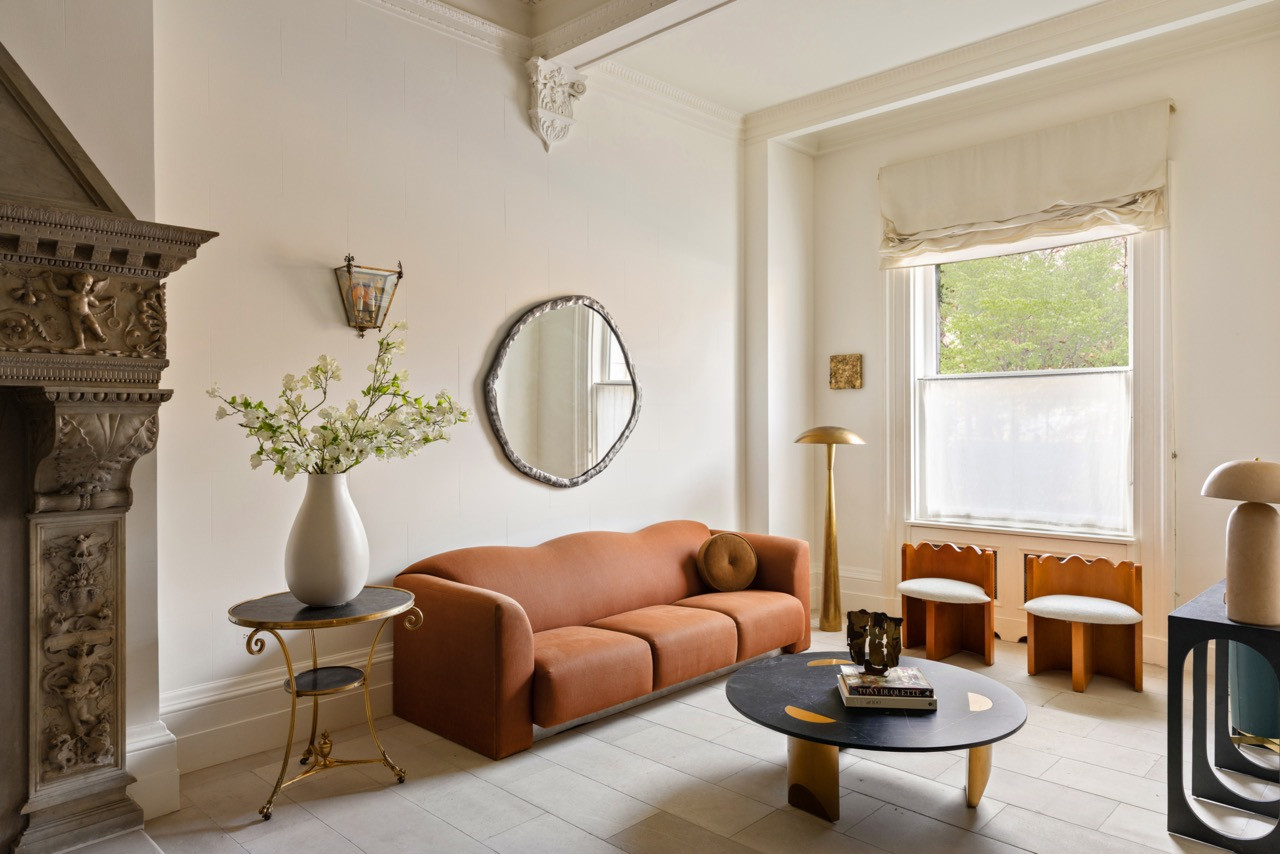 A curved, rust-colored sofa and a hammered brass-edged mirror furnish one of the home’s more contemporary sitting rooms
