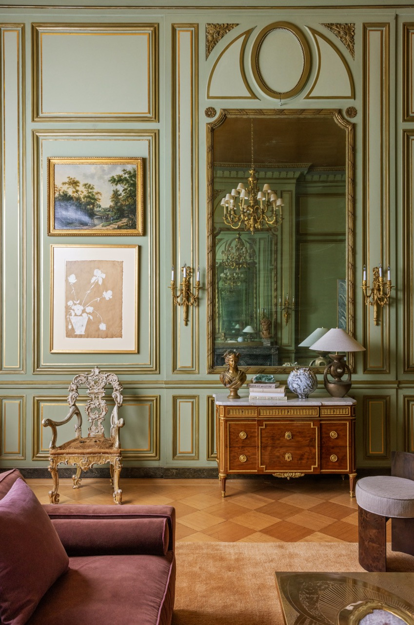 An antique giltwood armchair and a mahogany dresser sit against the Green Ballroom’s painted panelling