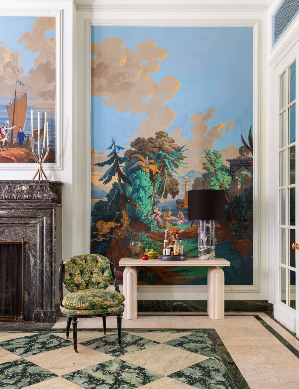 A mural of clouds and classical figures covers the wall behind a travertine console in the Dining Room, set with glass decanters and fruit