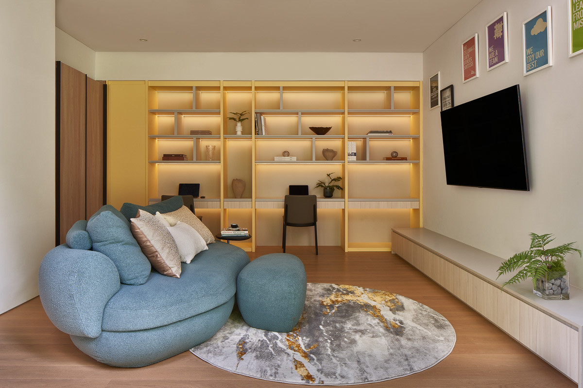 Twin study corners share one mustard-toned, backlit shelving unit, placed beside a cloud-blue armchair where the boys can linger close by