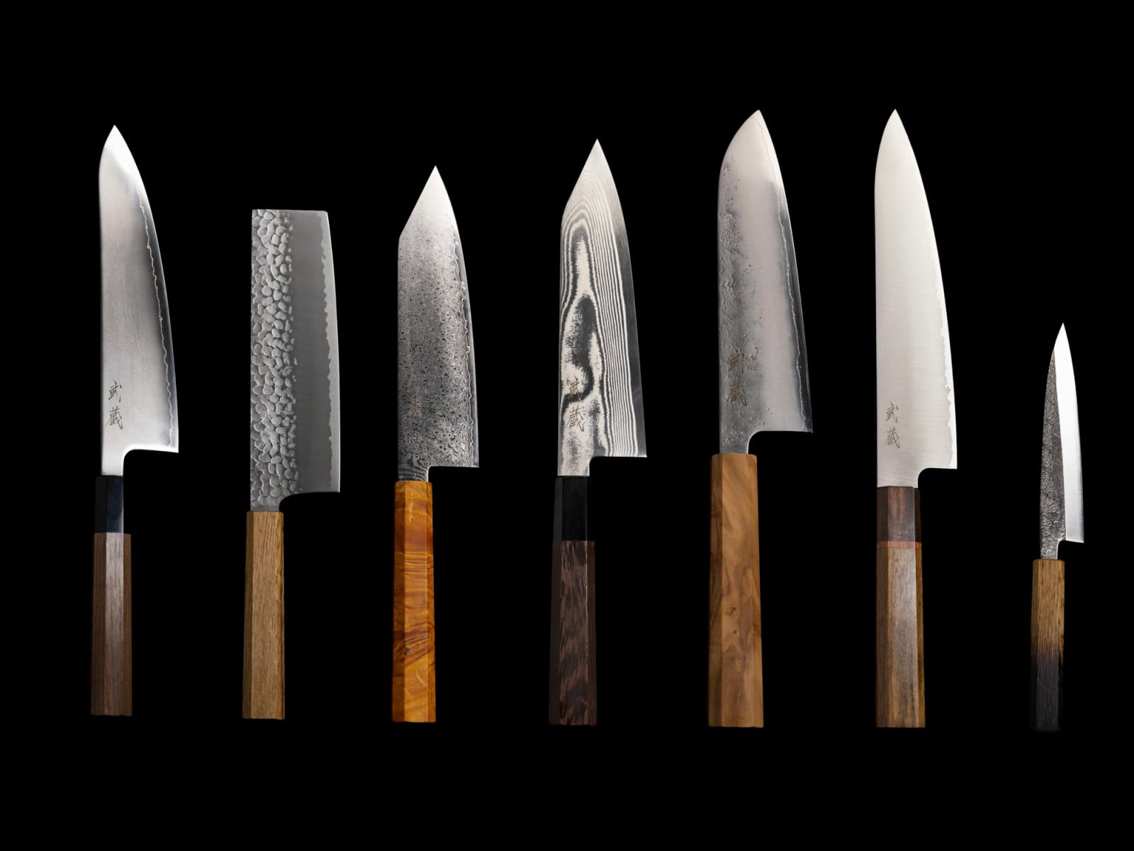 A collection of Japanese knives, featuring diverse blade patterns and elegant wooden handles.