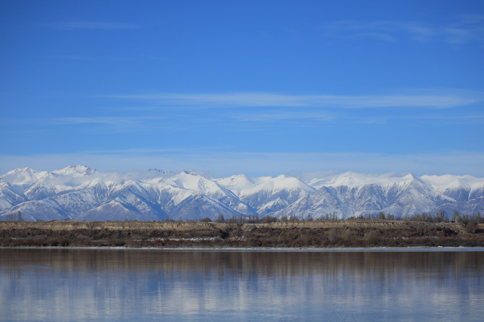Snow-capped mountains reflect in an Asian lake.