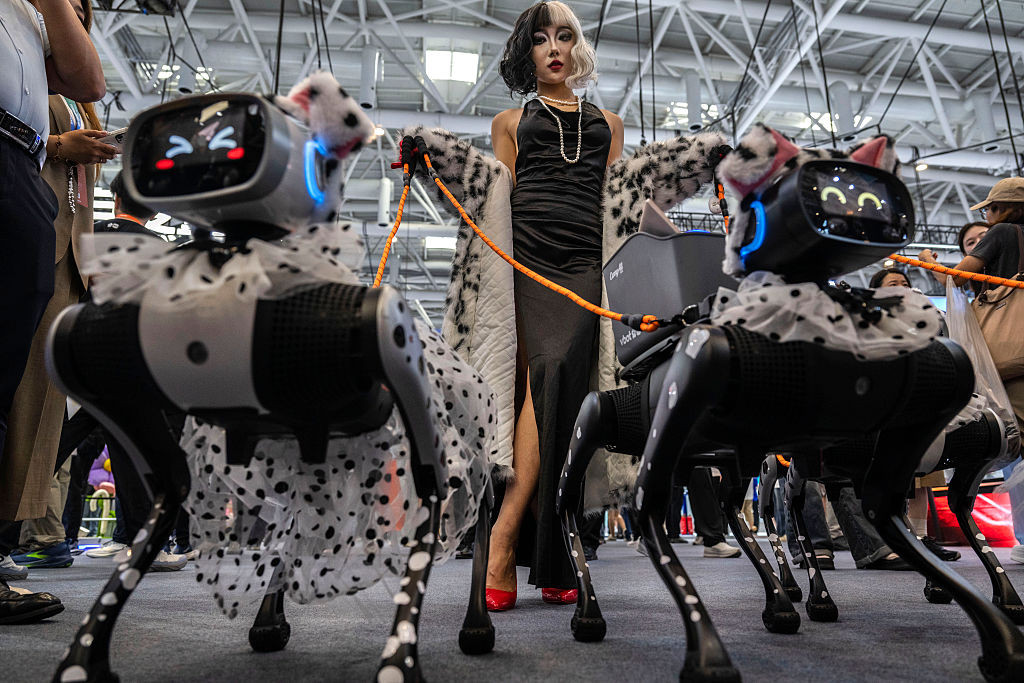 BEIJING, CHINA - AUGUST 19: A woman in costume walks with robot dogs from the company VBOT on the opening day of the World Robot Conference on August 19, 2026 in Beijing, China. Organizers say that more than 3,000 products are being shown at the multi day event as China showcases its rapidly growing robotics industry. (Photo by Kevin Frayer/Getty Images)
