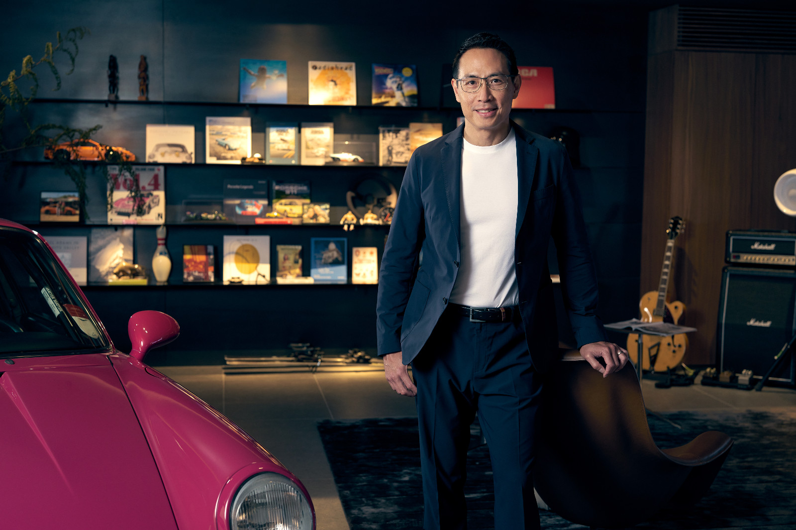 A portrait of Ko Chanond, a collector of rare assets in his curated private office, featuring a classic Porsche.