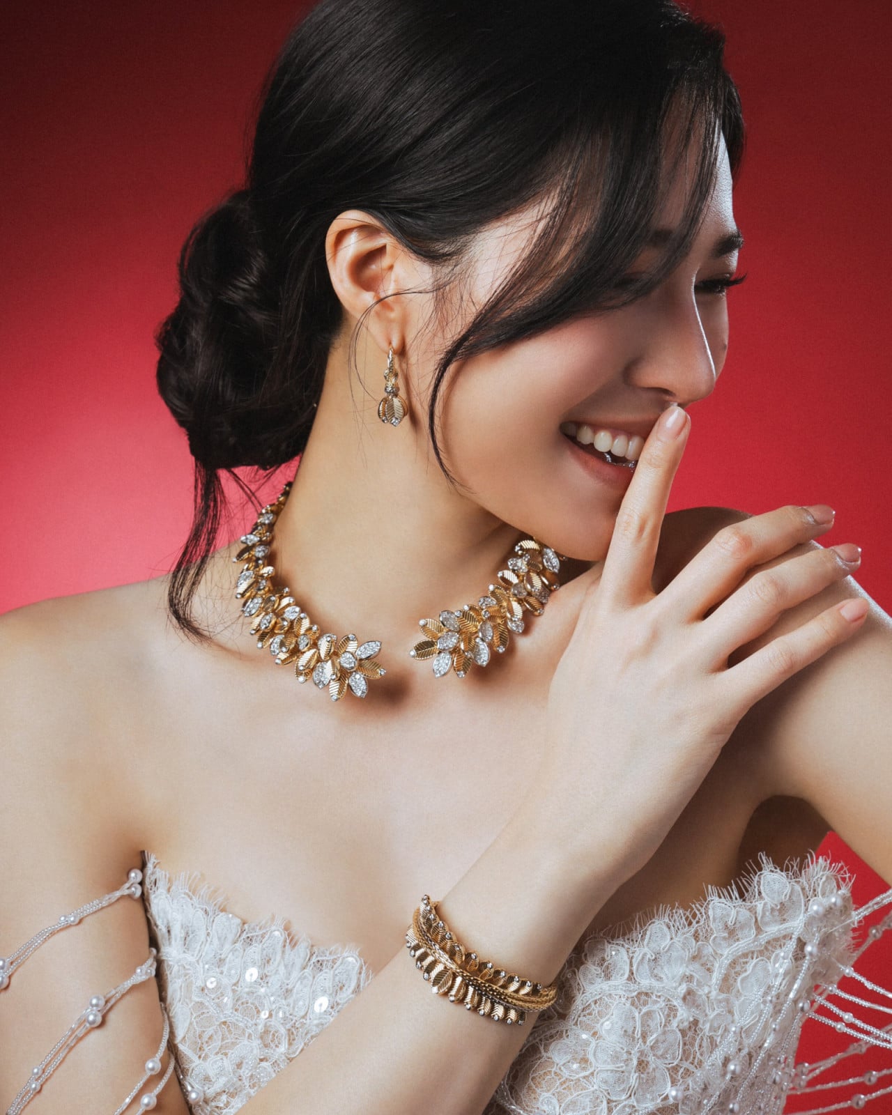 Lingling Kwong models a gold and diamond floral necklace, matching earrings, and bracelet, complemented by a beaded lace gown.