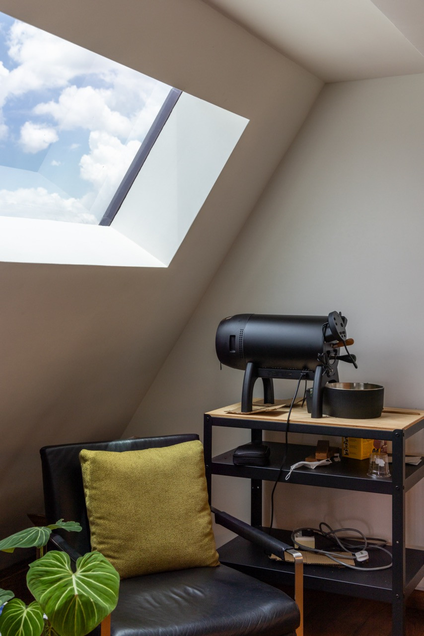 A skylight set into an angled ceiling lights a small seating corner furnished with a leather chair and side table