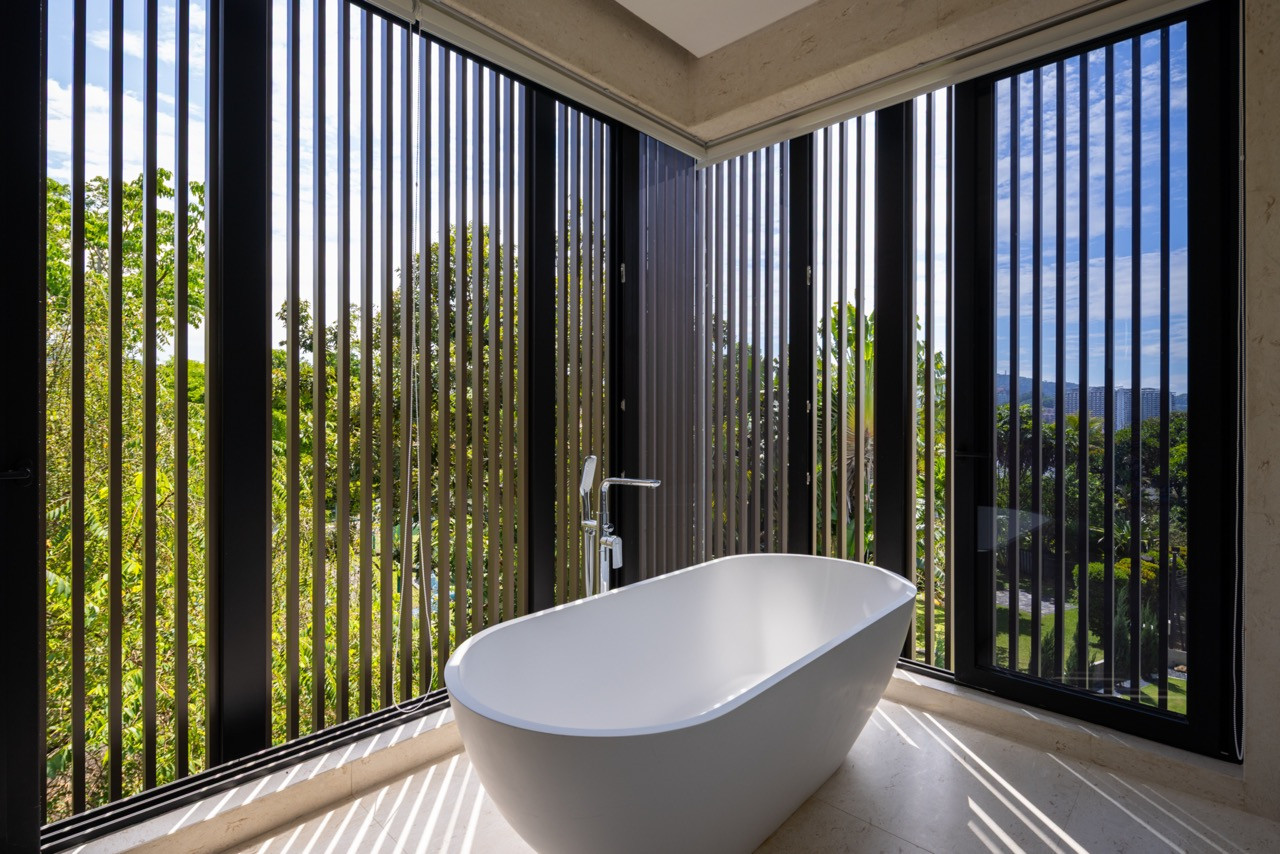 A freestanding bathtub sits behind a screen of vertical timber louvres, which filter the view out to the garden and hills while preserving privacy