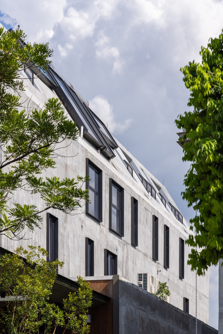 The long concrete side elevation features narrow punched windows and sloped skylights along the roof edge