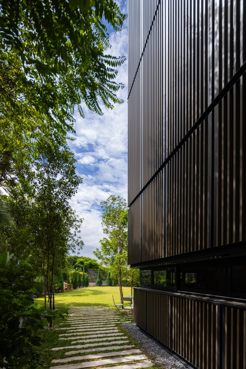 A slatted black screen wraps one corner of the house, overlooking the lawn at the rear of the property