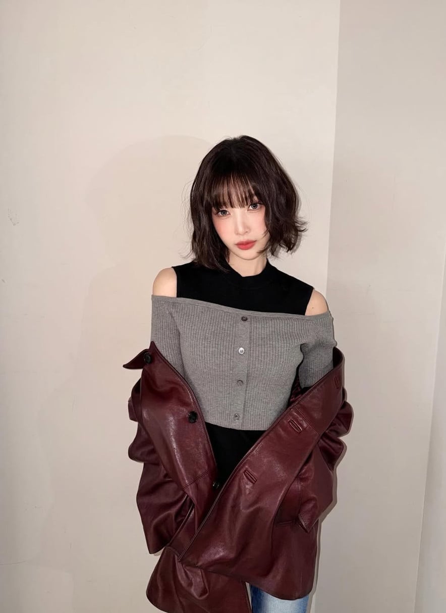 A woman models a ribbed off-the-shoulder top paired with a burgundy leather jacket.