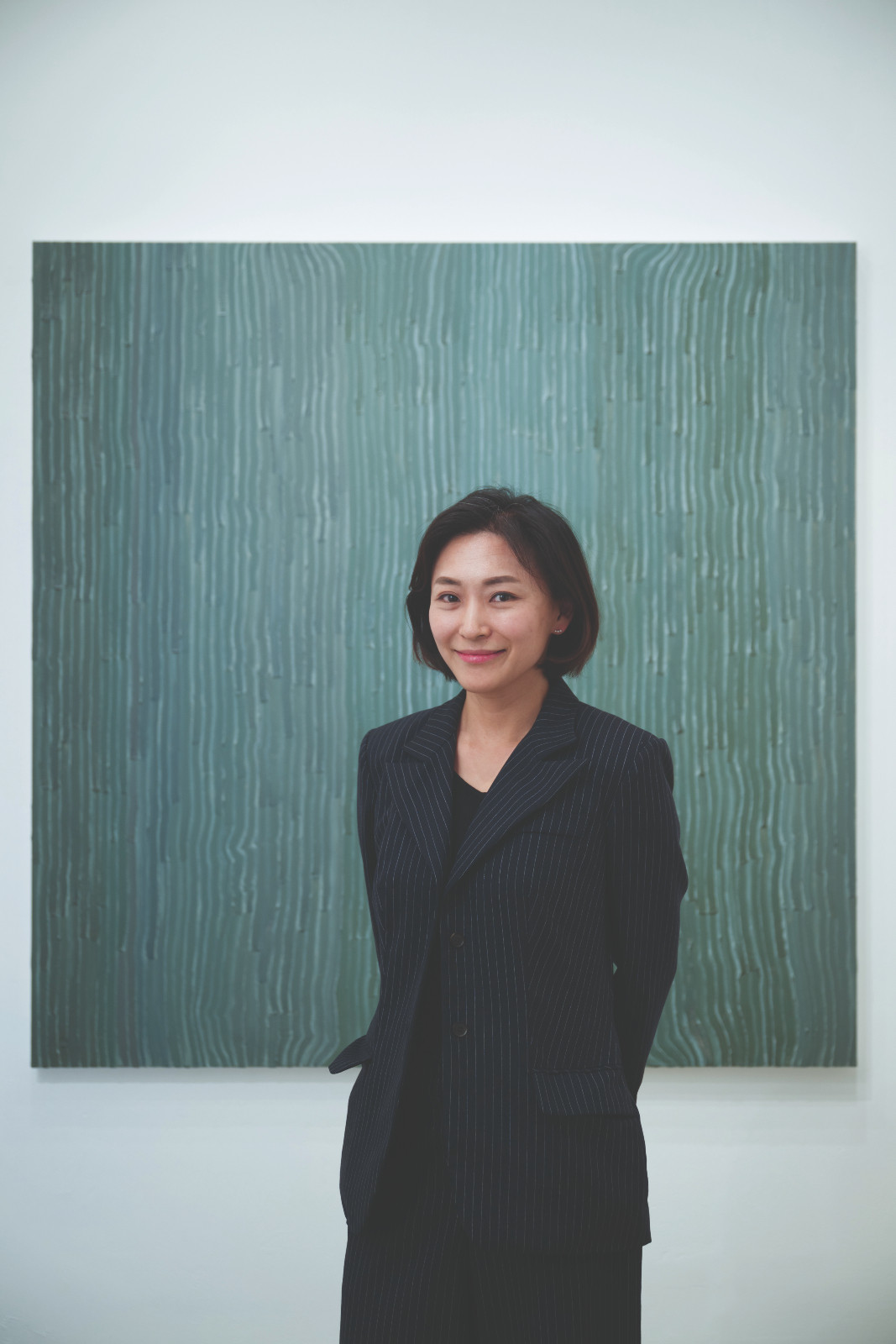 Mirinai Choi, director of Soluna Fine Art, standing before an abstract painting by Kim Keun-tai made using traditional Korean stone powder. (Photo: courtesy of Soluna Fine Art)