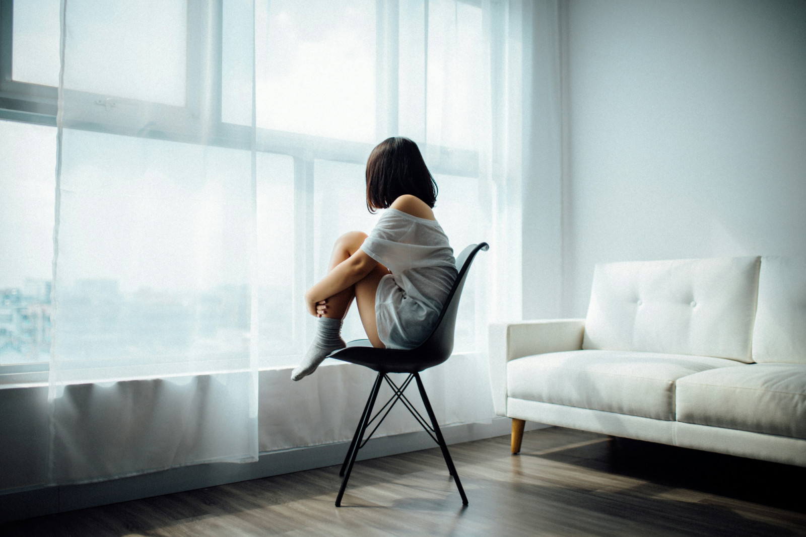 A woman sits quietly by a window, finding a moment for reflection and inner strength.