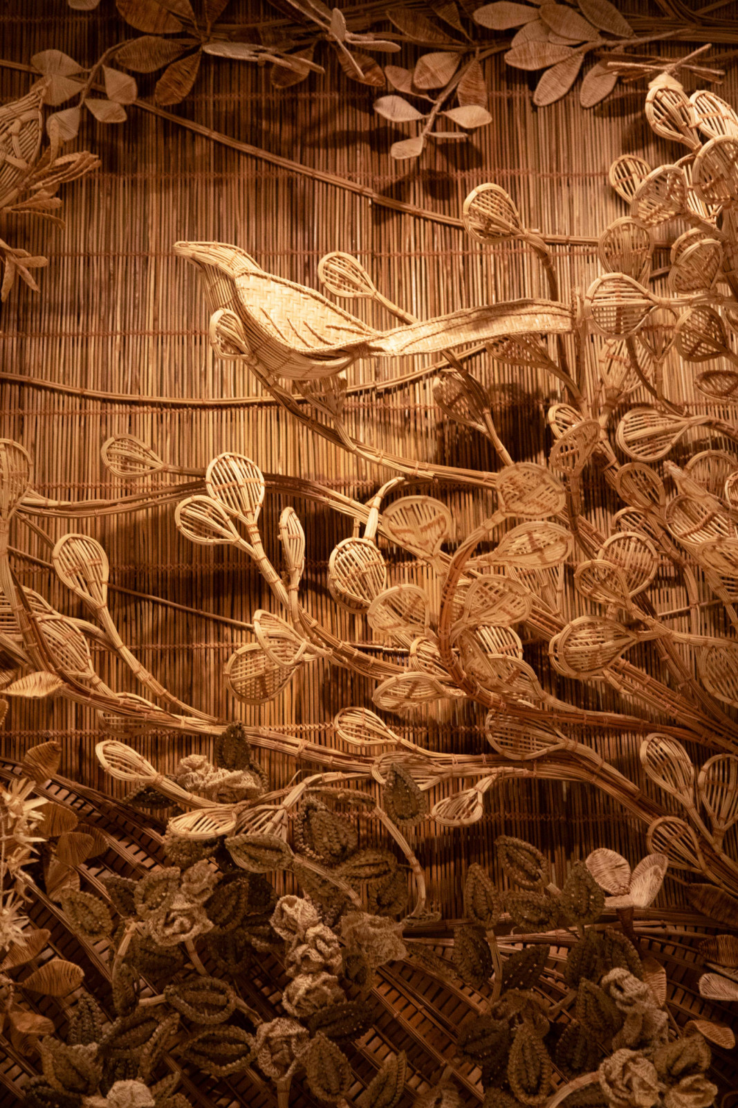 A close-up of Korakot Aromdee and Vasana Saima's scenography, where birds, budding branches and flowers are rendered in meticulous woven detail