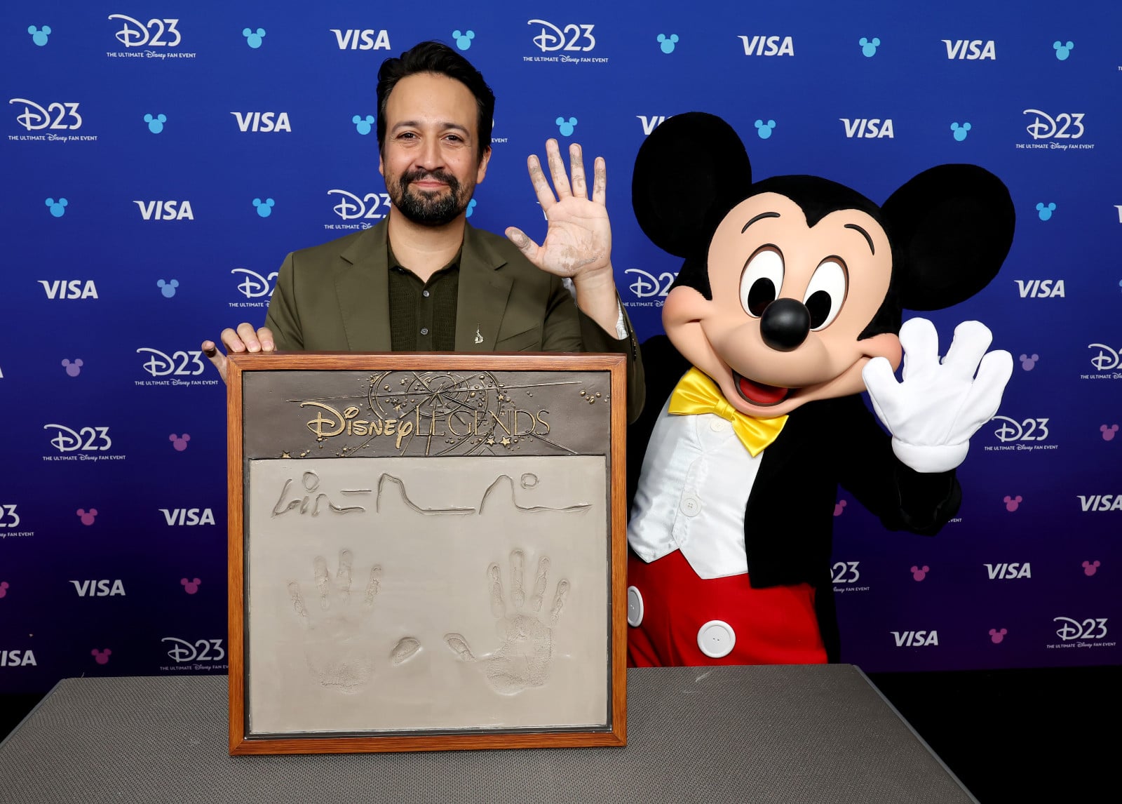 Lin-Manuel Miranda displays his Disney Legends handprint plaque with Mickey Mouse at the D23 fan event.