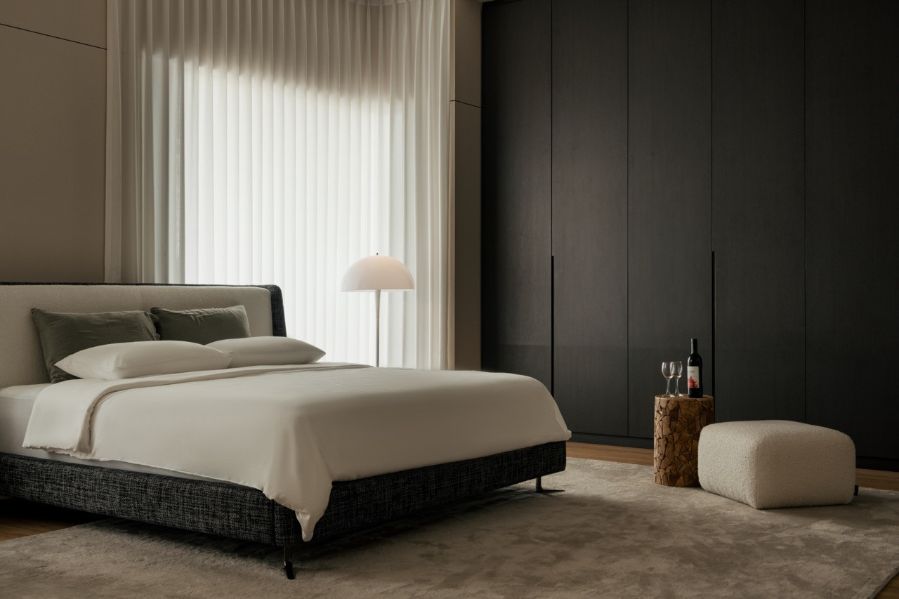 One of the home’s four bedrooms, with a dark wardrobe wall and sheer curtains softening the light from the window
