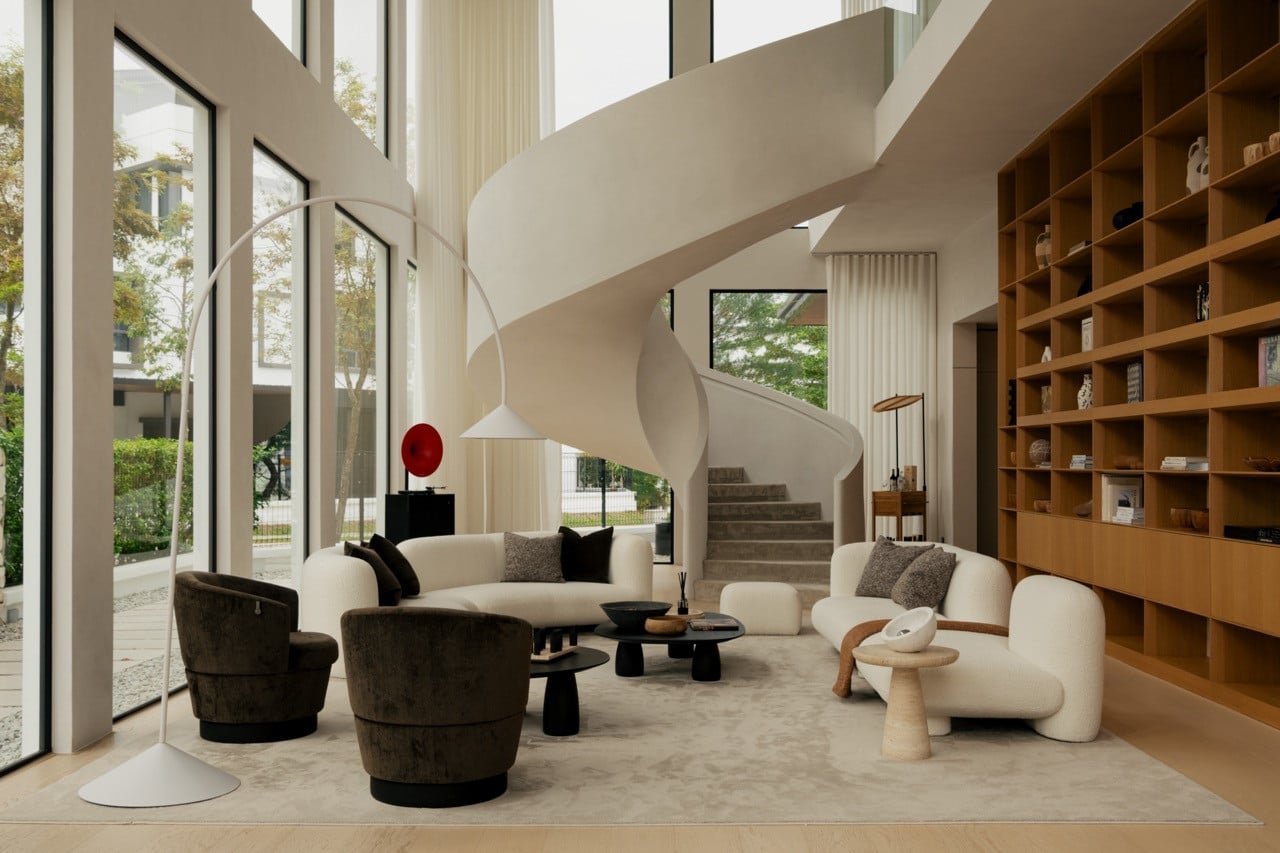 The spiral staircase in full view against the floor-to-ceiling bookshelf, with a reading nook set beneath the double-height ceiling