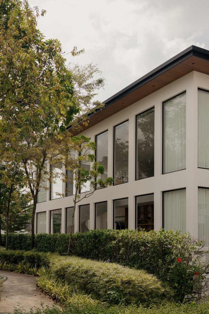 The home’s exterior, its glazed double-height volume set back behind hedging and landscaping