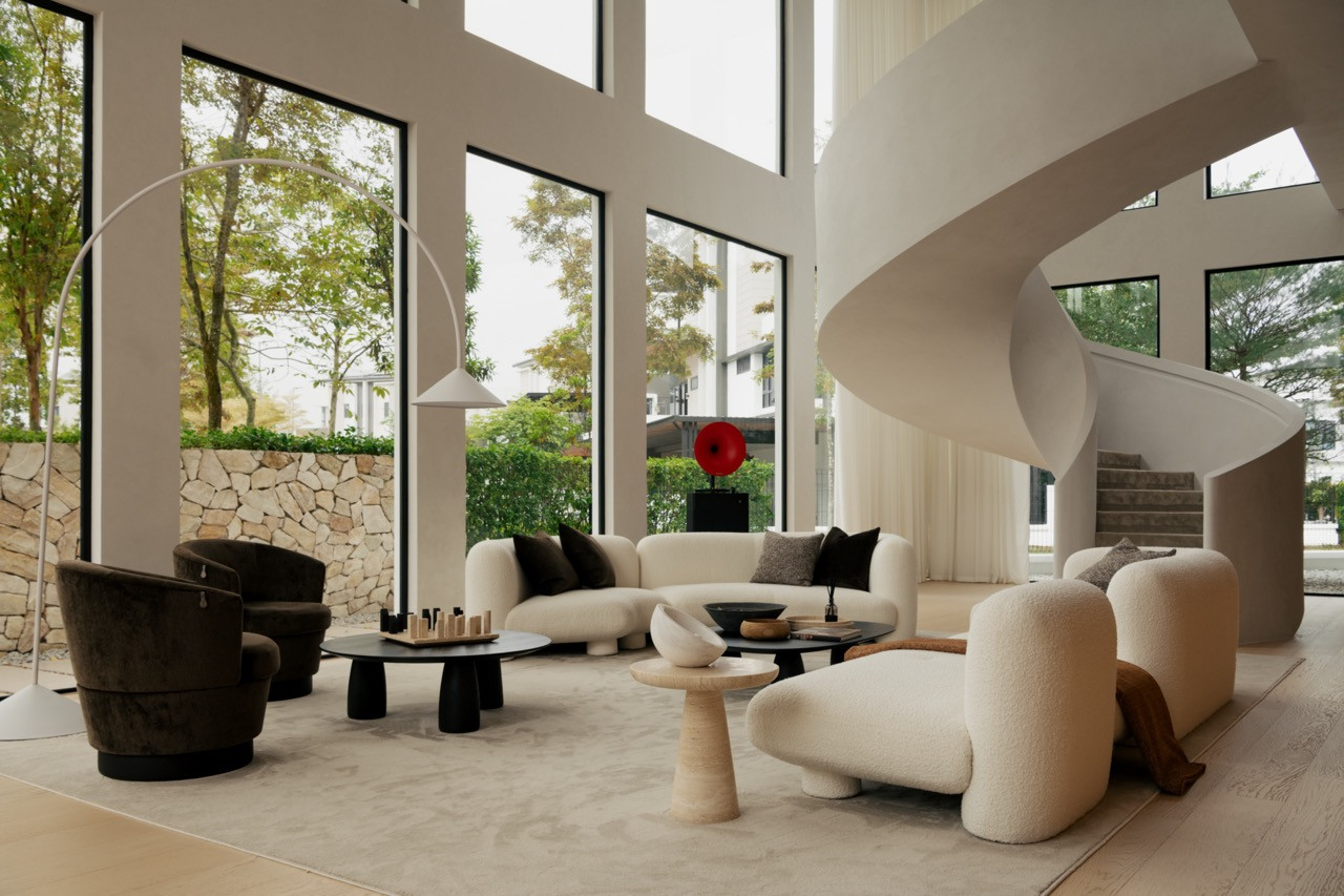 The double-height living area, with the sculptural spiral staircase rising beside floor-to-ceiling glass and a boucle sofa arrangement