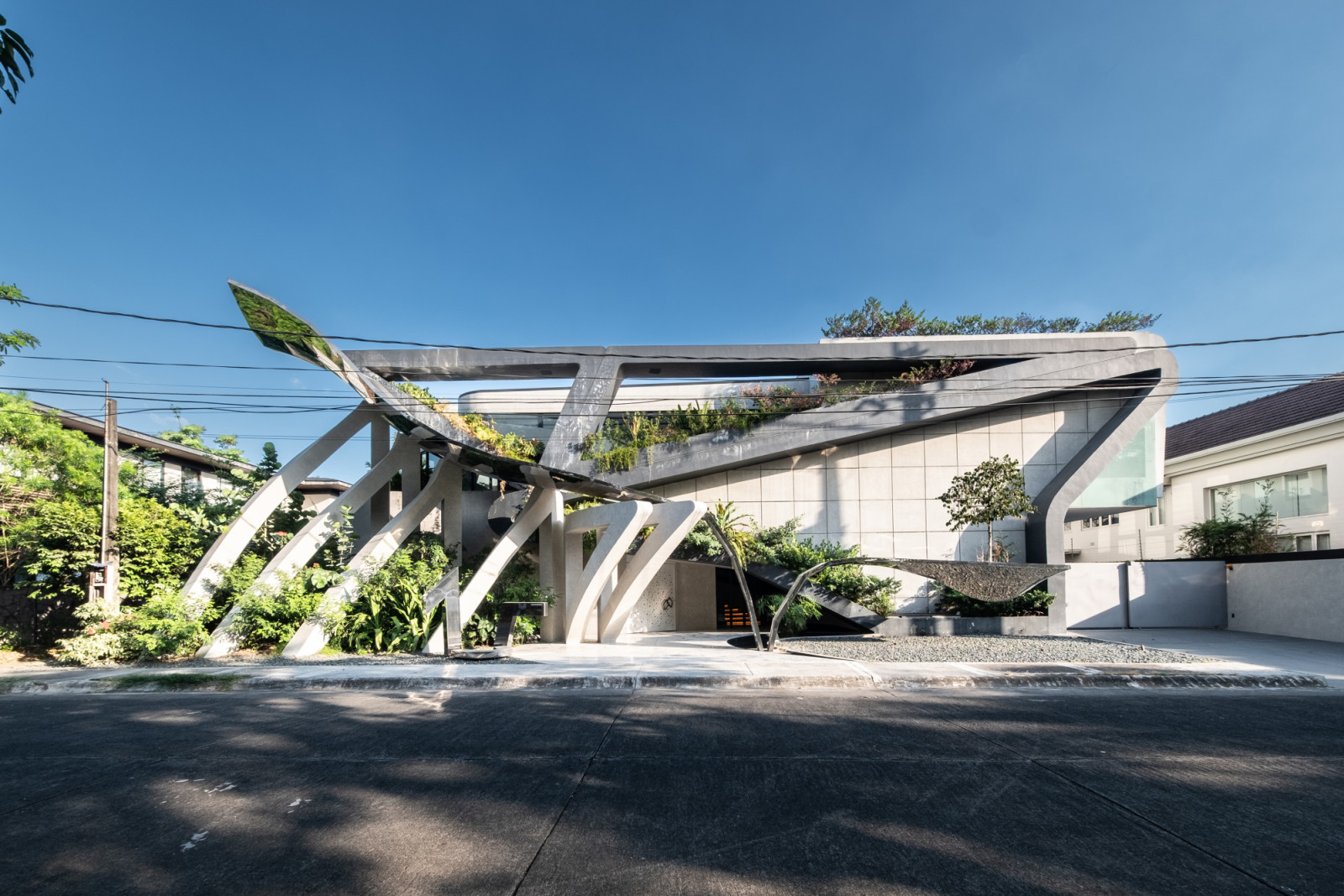 Origami-inspired concrete pillars form a dramatic, open boundary between the street and the home