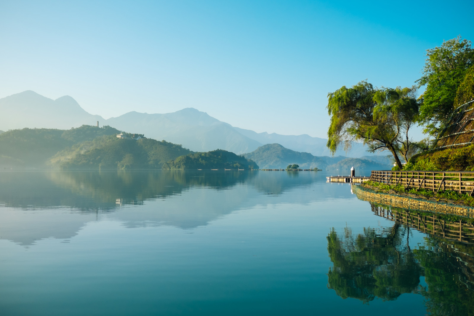 Reflection of trees, mountains, and islands on the clear water lake, sun moon lake. The lake has very clear water and can reflect trees and mountains on its surface.