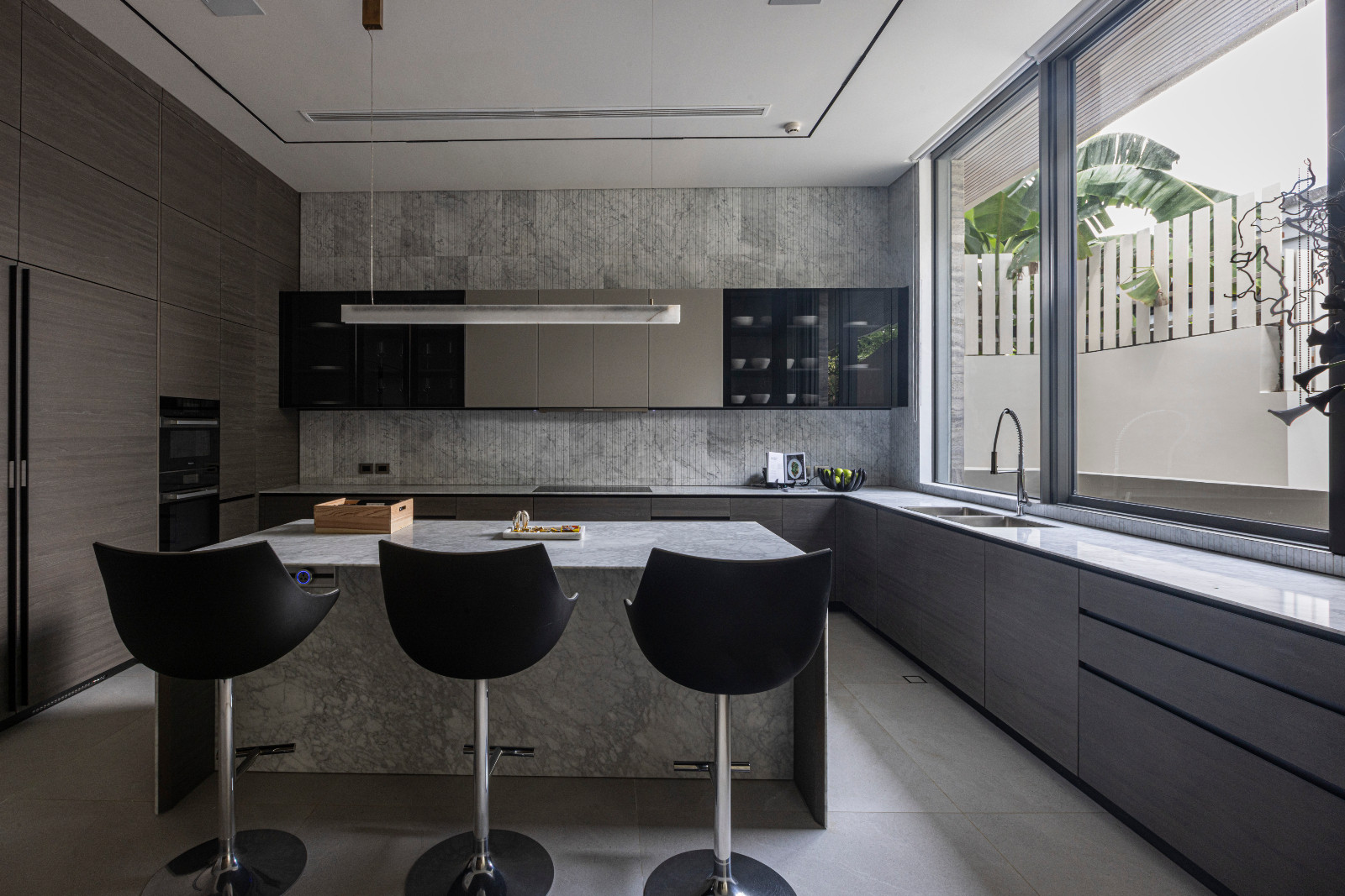 Cabinet system and stone countertop by Valcucine with appliances by Miele, Passion stools in upholstered leather by Cassina