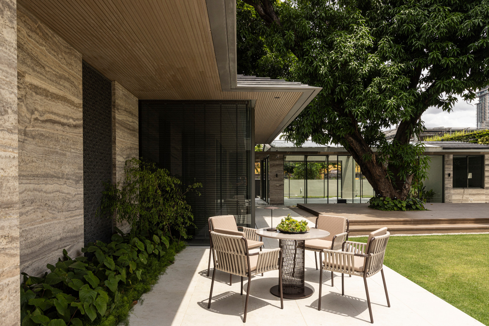 Iranian Travertine wall with laser-cut metal sunscreens in a custom pattern paired with a Mesh dining table and Net dining chairs from Kettal