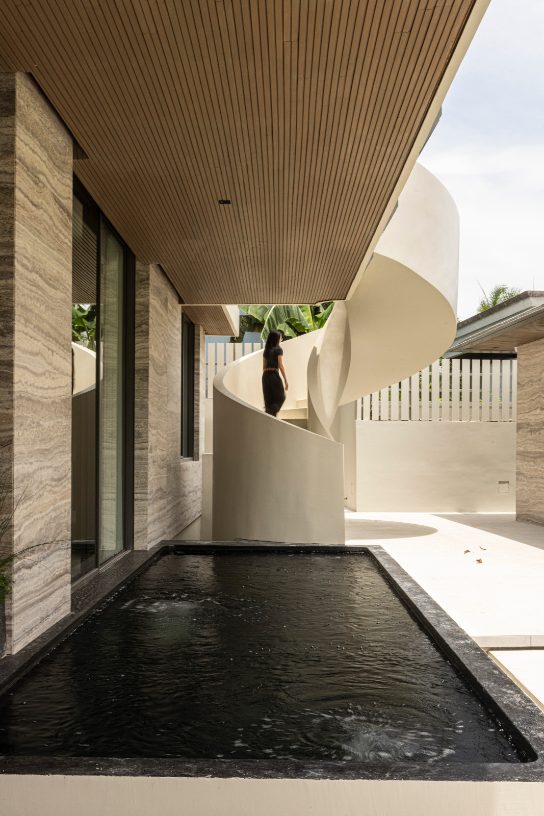 Iranian Travertine exterior wall cladding complements a sculptural spiral staircase