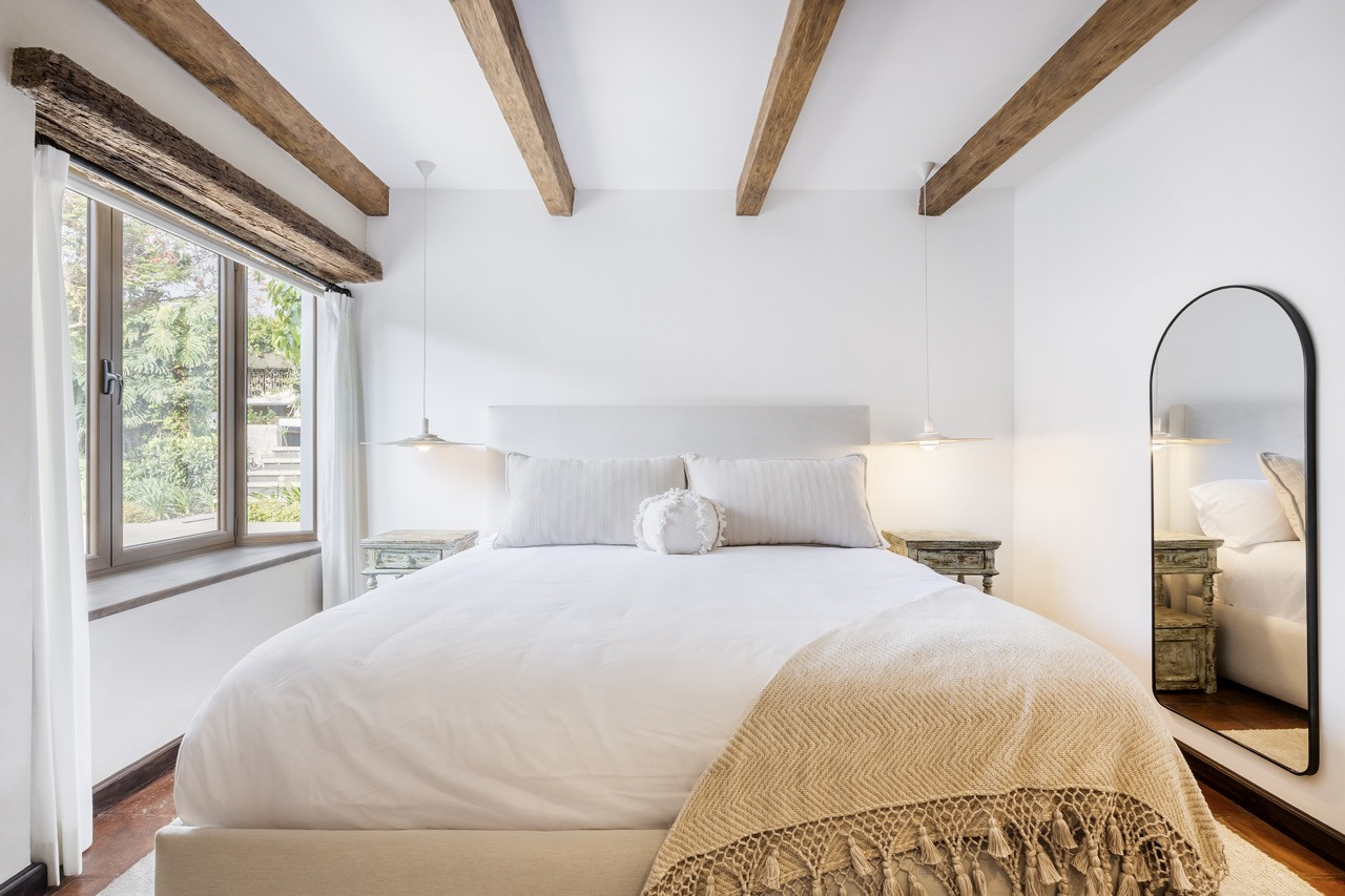 Reclaimed wood beams and a restored wood floor are among the original elements retained in this bedroom