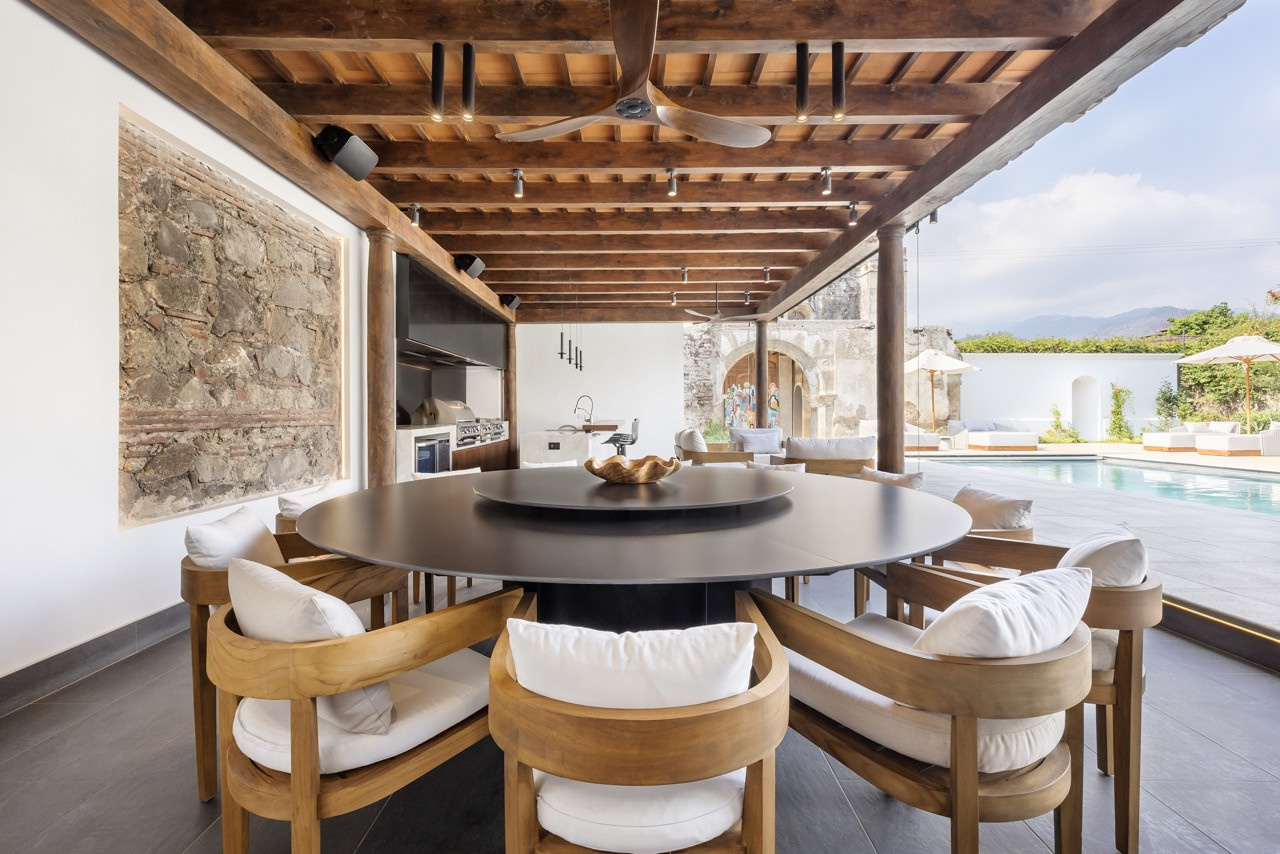 The outdoor terrace features a twelve-seat dining table beside the excavated stone wall