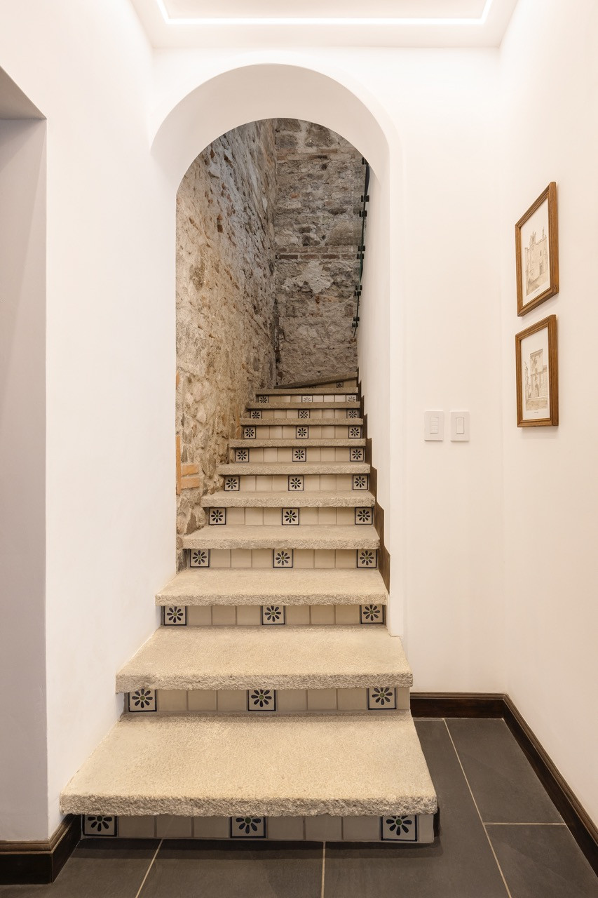 A tiled staircase descends past exposed stone toward the spa area built beneath the old arch