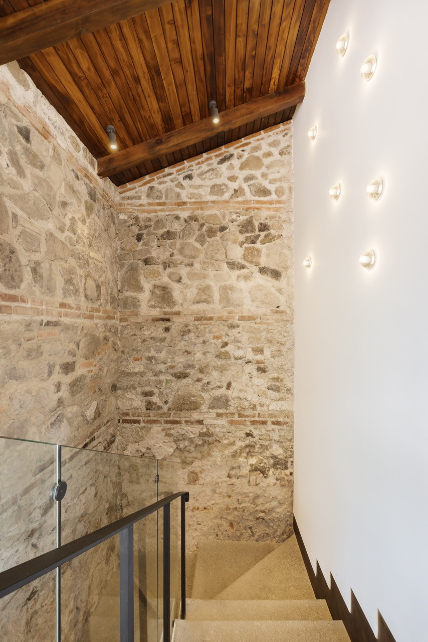 A stairwell exposes the original stone and brick construction, left visible rather than plastered over