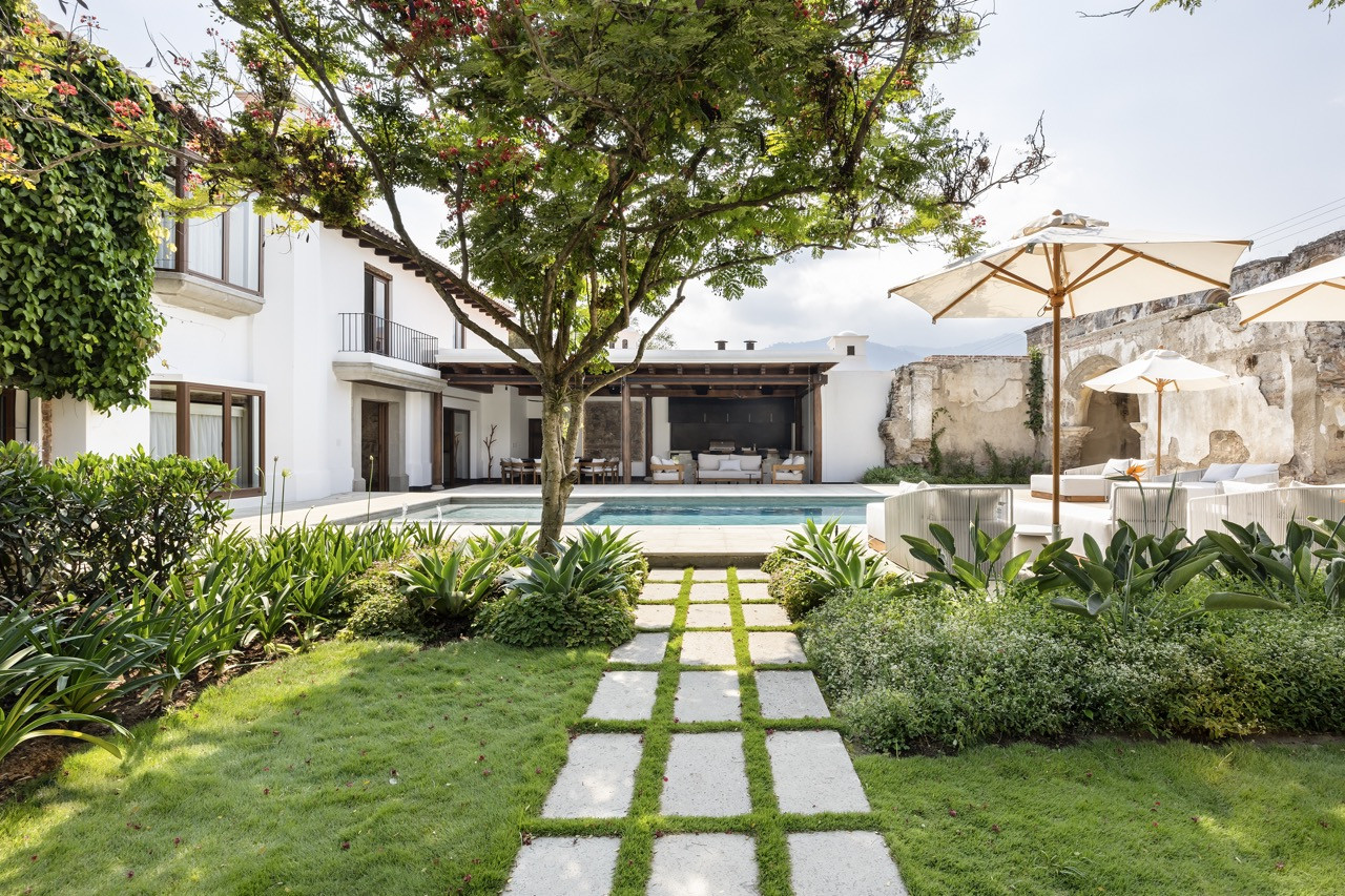 A stepping-stone path through the garden leads toward the pool and the house’s Spanish colonial facade