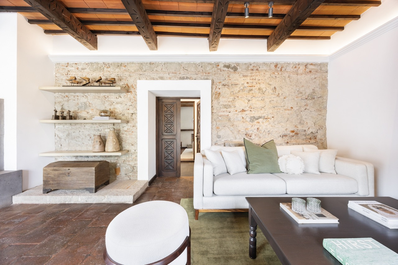 Teak-trimmed daybeds sit beneath an umbrella near a weathered wooden door original to the property