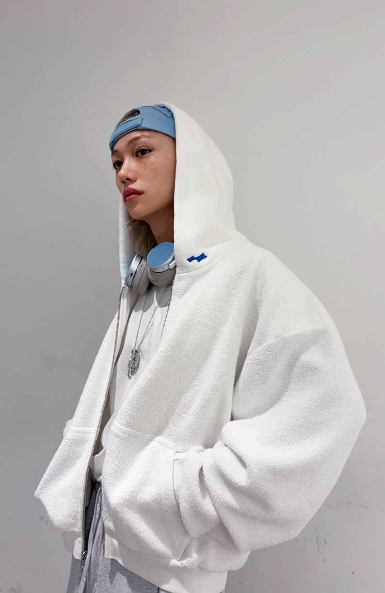 Stray Kids' Felix exudes relaxed style in a textured white hoodie, light blue cap, and headphones.