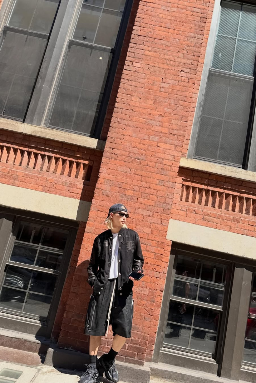 Stray Kids' Felix wears a black varsity jacket, shorts, and sunglasses.