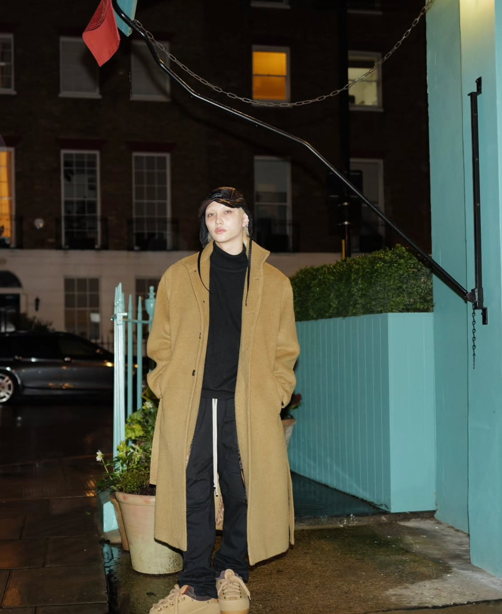 Stray Kids member Felix dons a classic camel coat and dark streetwear during an evening appearance.