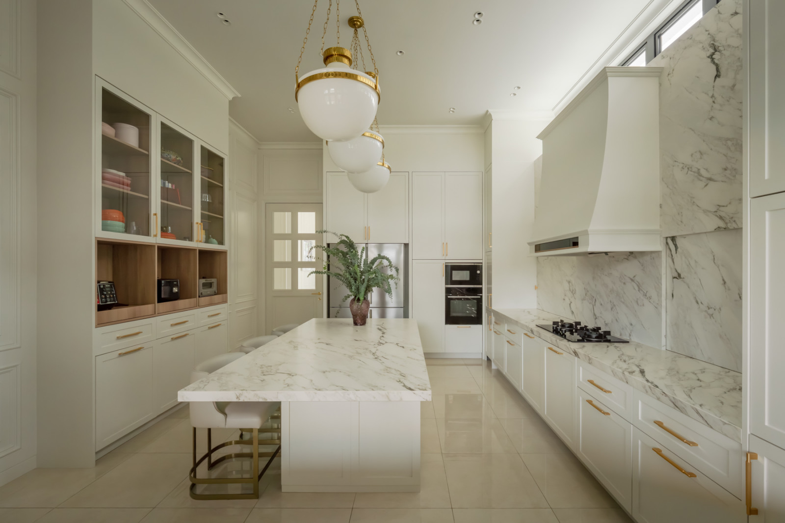 Marble countertops and a matching hood run along one wall of the kitchen, with a glass-fronted display cabinet opposite