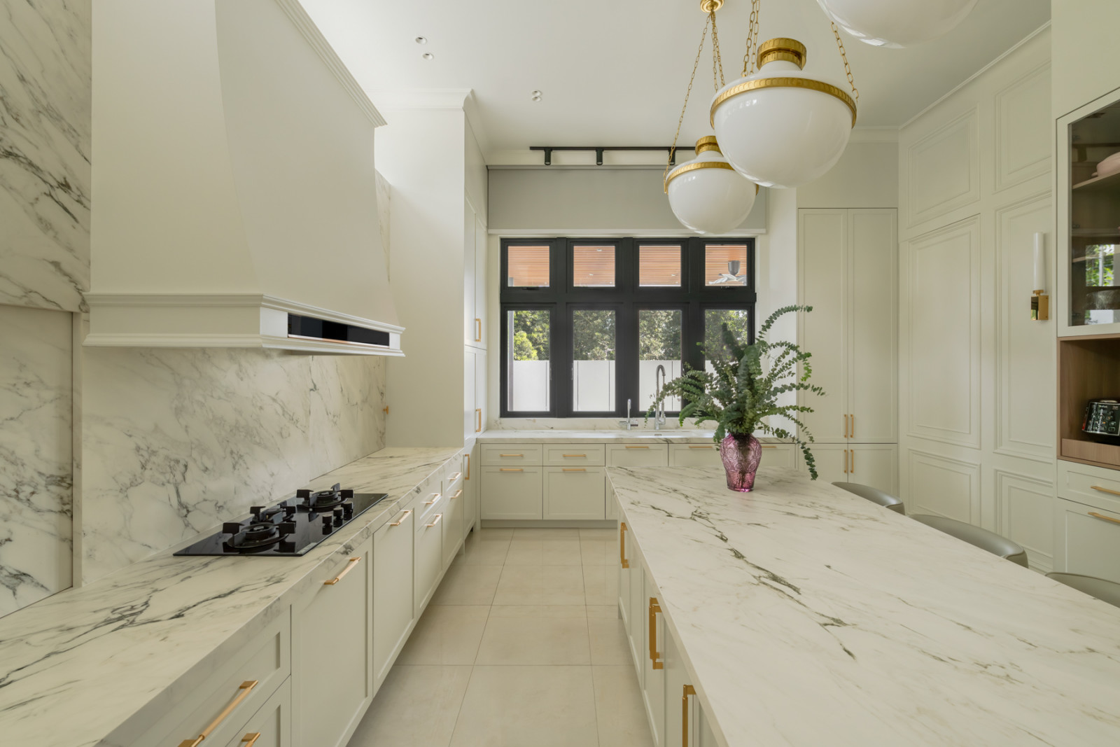 Marble counters and a matching backsplash run the length of the kitchen, finished with brass hardware