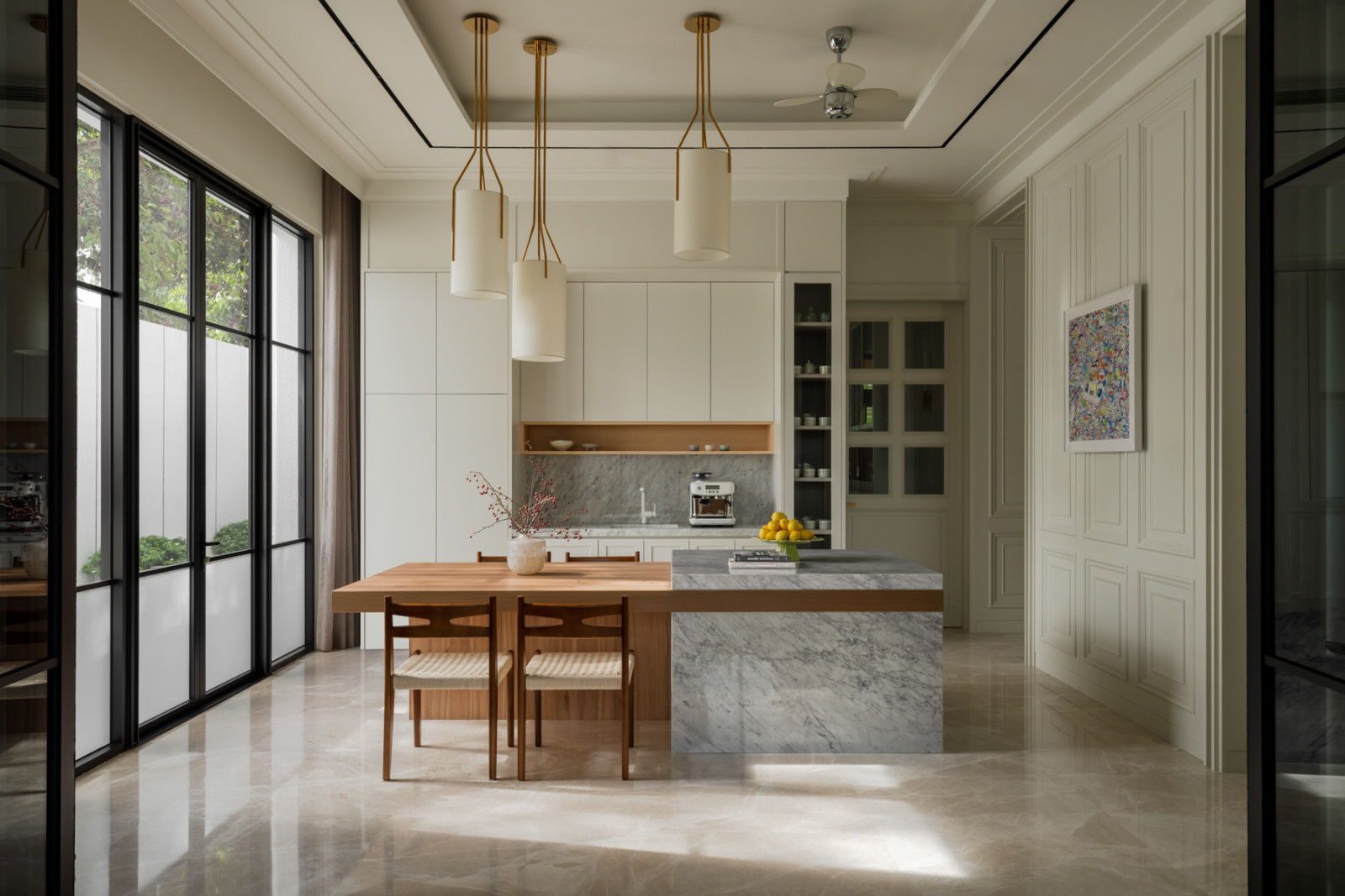 A marble-topped island and timber dining table sit beneath a row of cylindrical pendant lights in the kitchen’s breakfast area