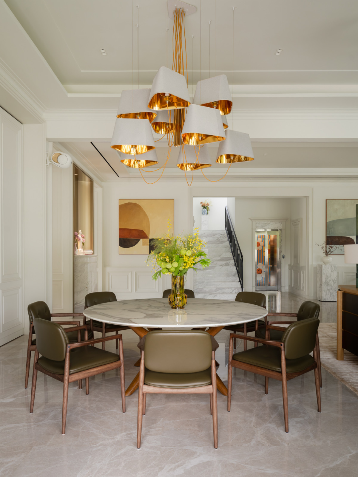 The dining space opens onto the marble staircase, with the home’s lift visible beyond