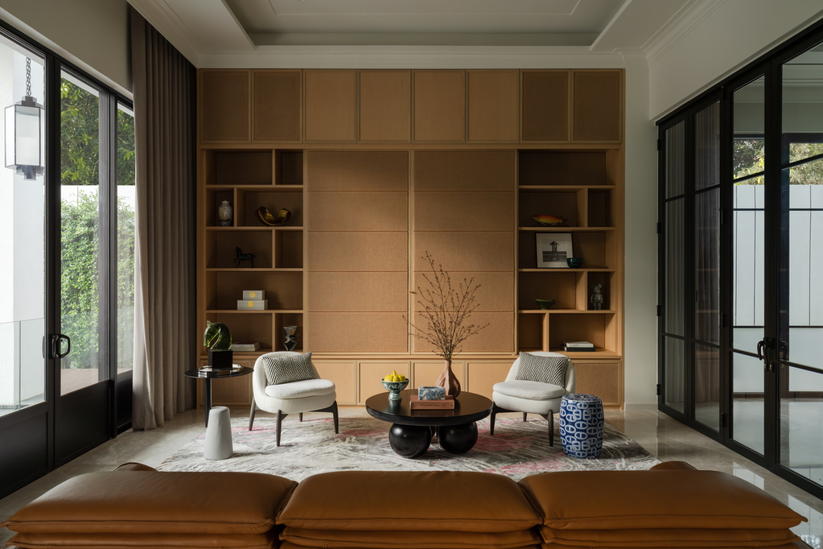 A pair of armchairs and a black stone-based coffee table sit before built-in shelving in the media room