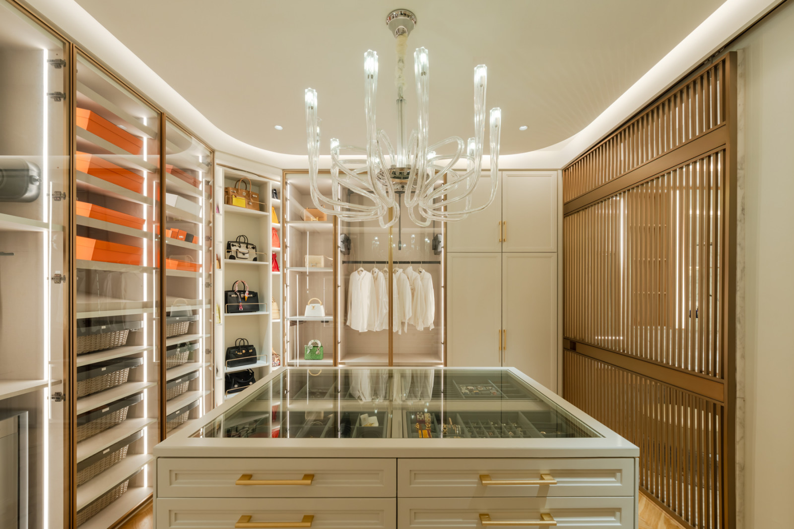 Hermès pieces and the handbag collection are displayed on illuminated shelving around a central jewellery island