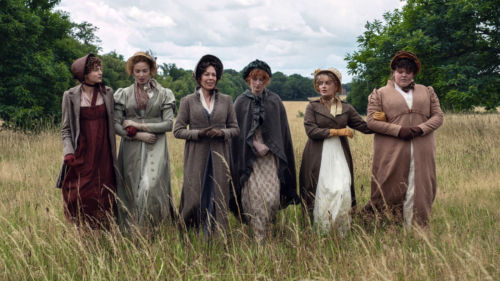 Women in period attire and bonnets stroll through a meadow, evoking the world of Jane Austen.