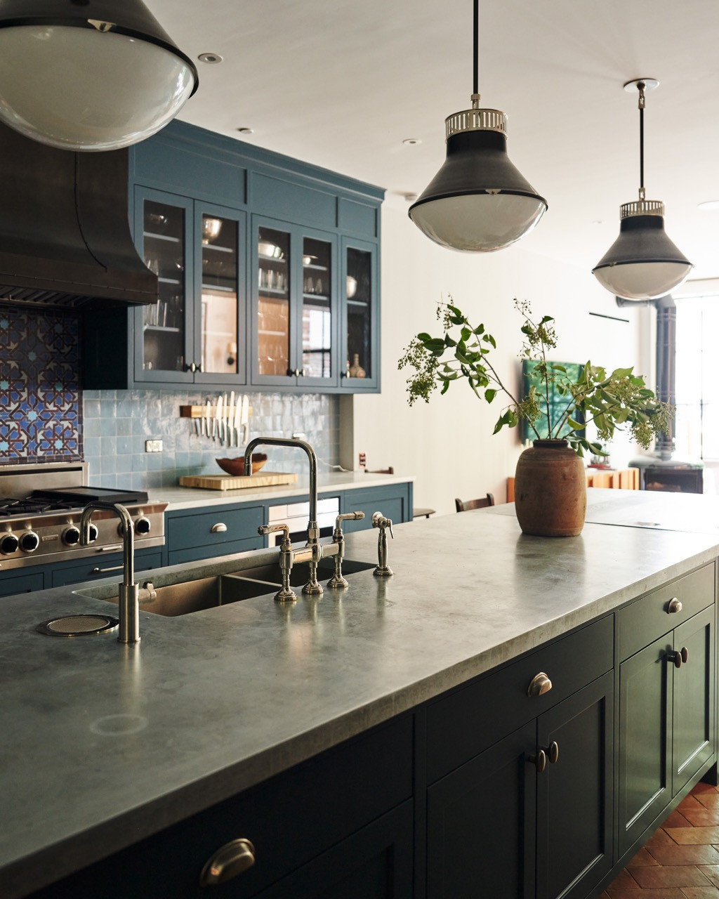 The kitchen, relocated to the garden level, with blue cabinetry, patterned tile, and a stone-topped island