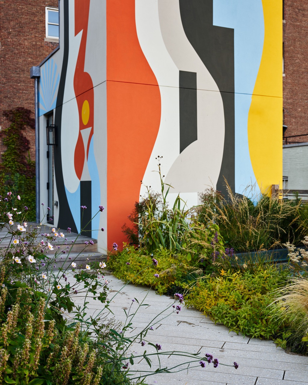The bold, abstract rooftop mural by artist Robbie Simon, painted across the building’s upper wall above the garden