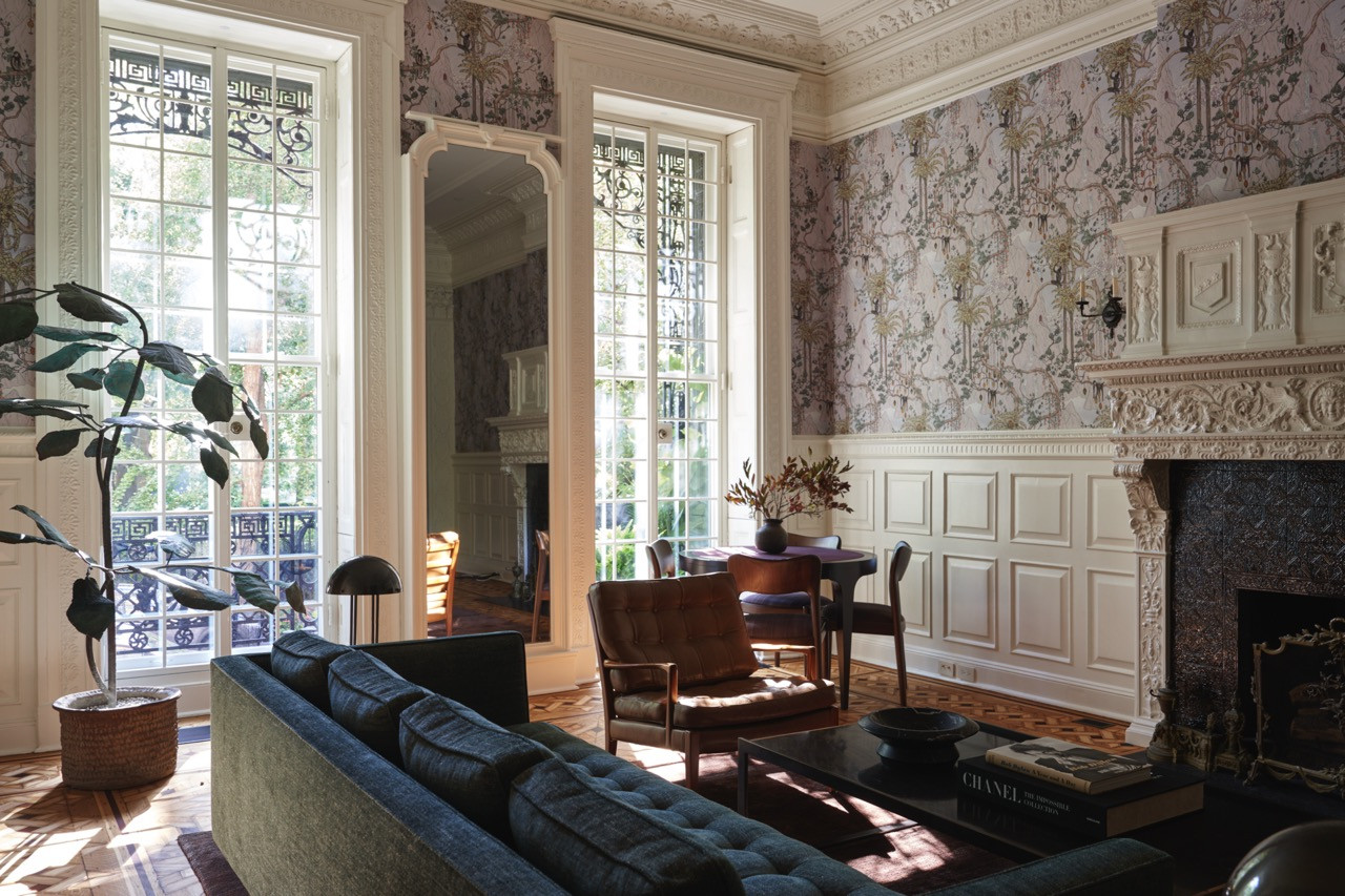 A parlour-floor sitting room hung with the David Wiseman wallpaper depicting monkeys and foliage, its ornate plasterwork and marble fireplace intact