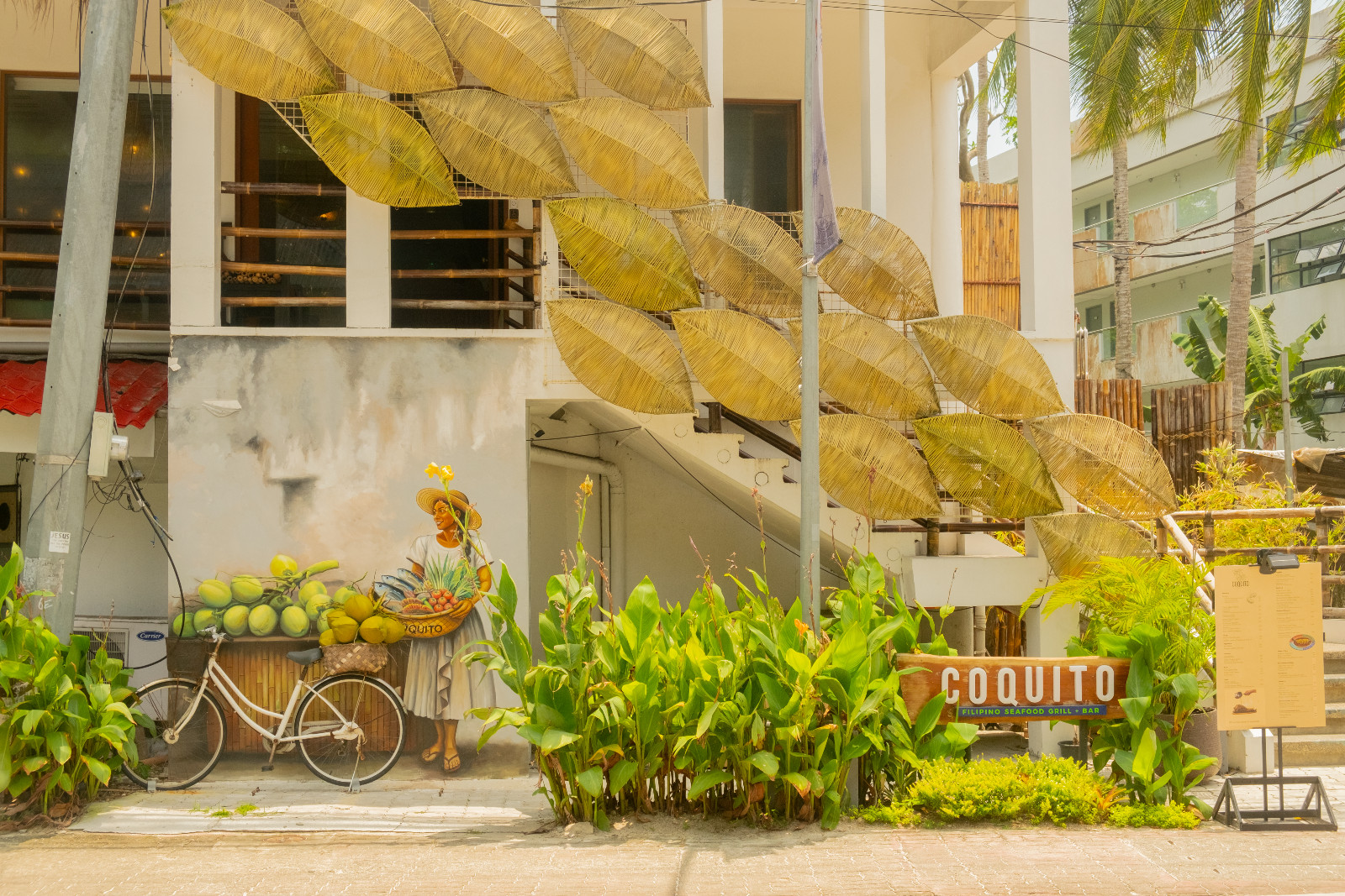 A glimpse of Filipino craftsmanship on display at Coquito Boracay, with a mural of a woman tending to local produce created by Japs Avelino