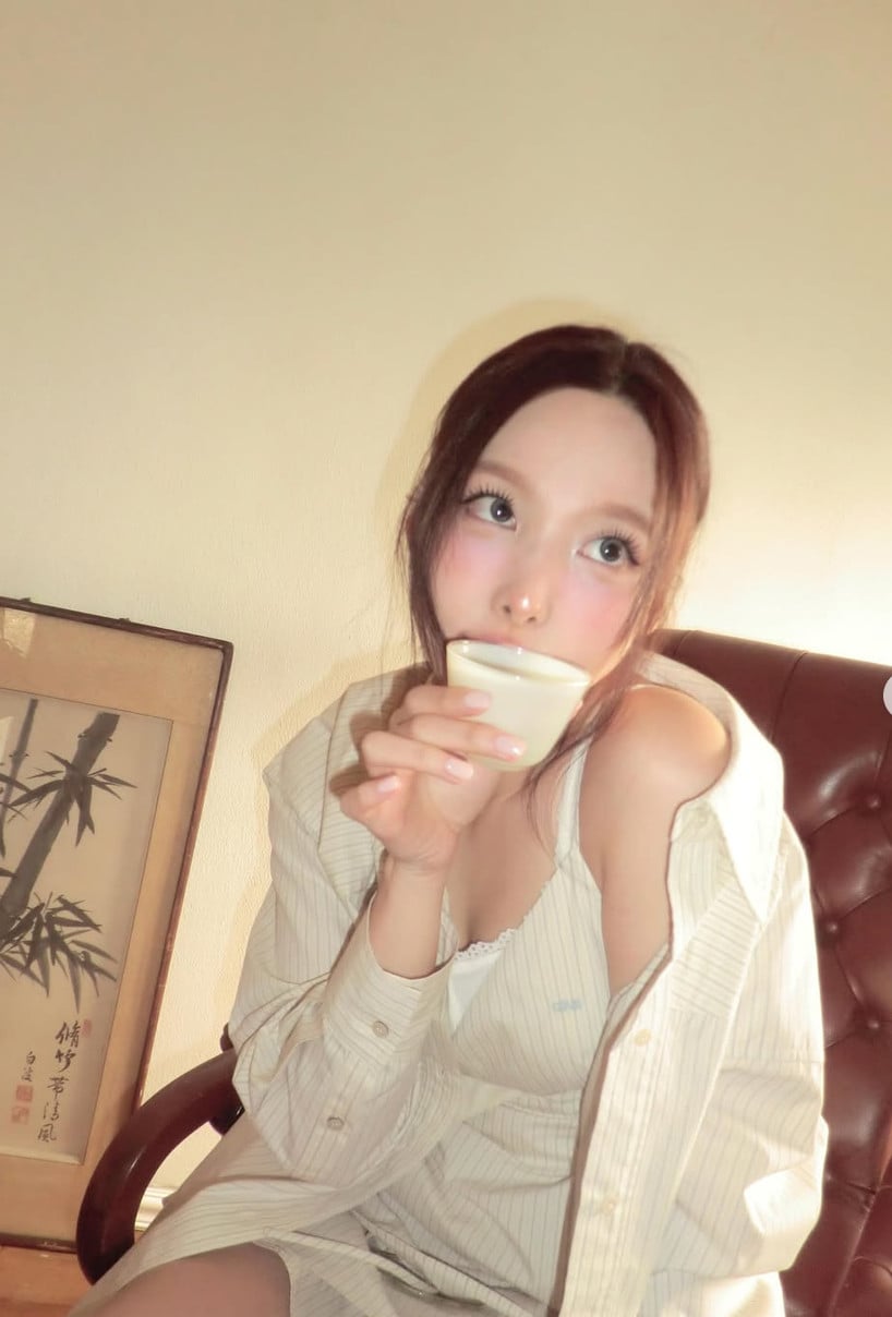 Nayeon, member of TWICE, sips from a delicate cup in a relaxed indoor moment.