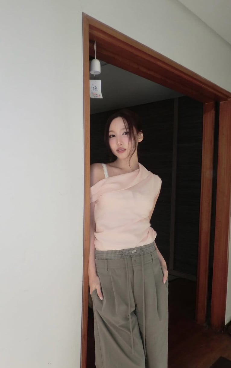 TWICE's Nayeon pairs a soft pink off-shoulder top with olive trousers.